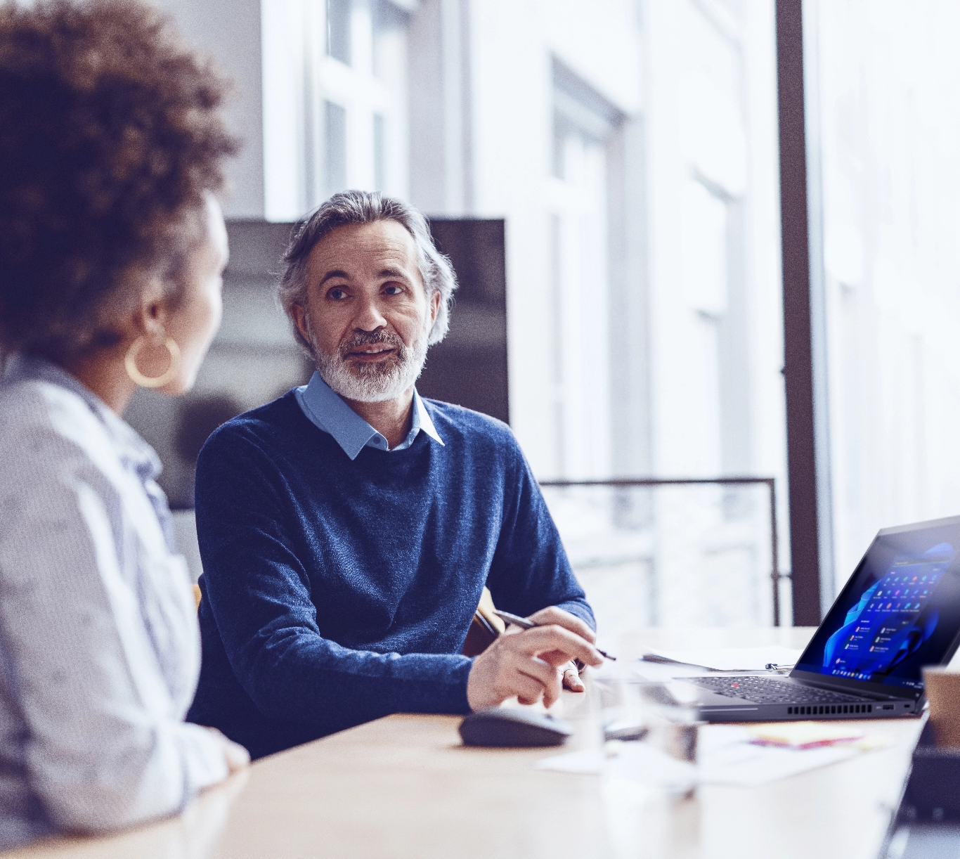 Woman and man sitting in office with laptop with Windows 11 on-screen discussing Windows 11 migration.